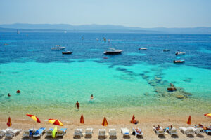 Brač island holidays tourists enjoying their vacation on a beach, swimming and sunbathing