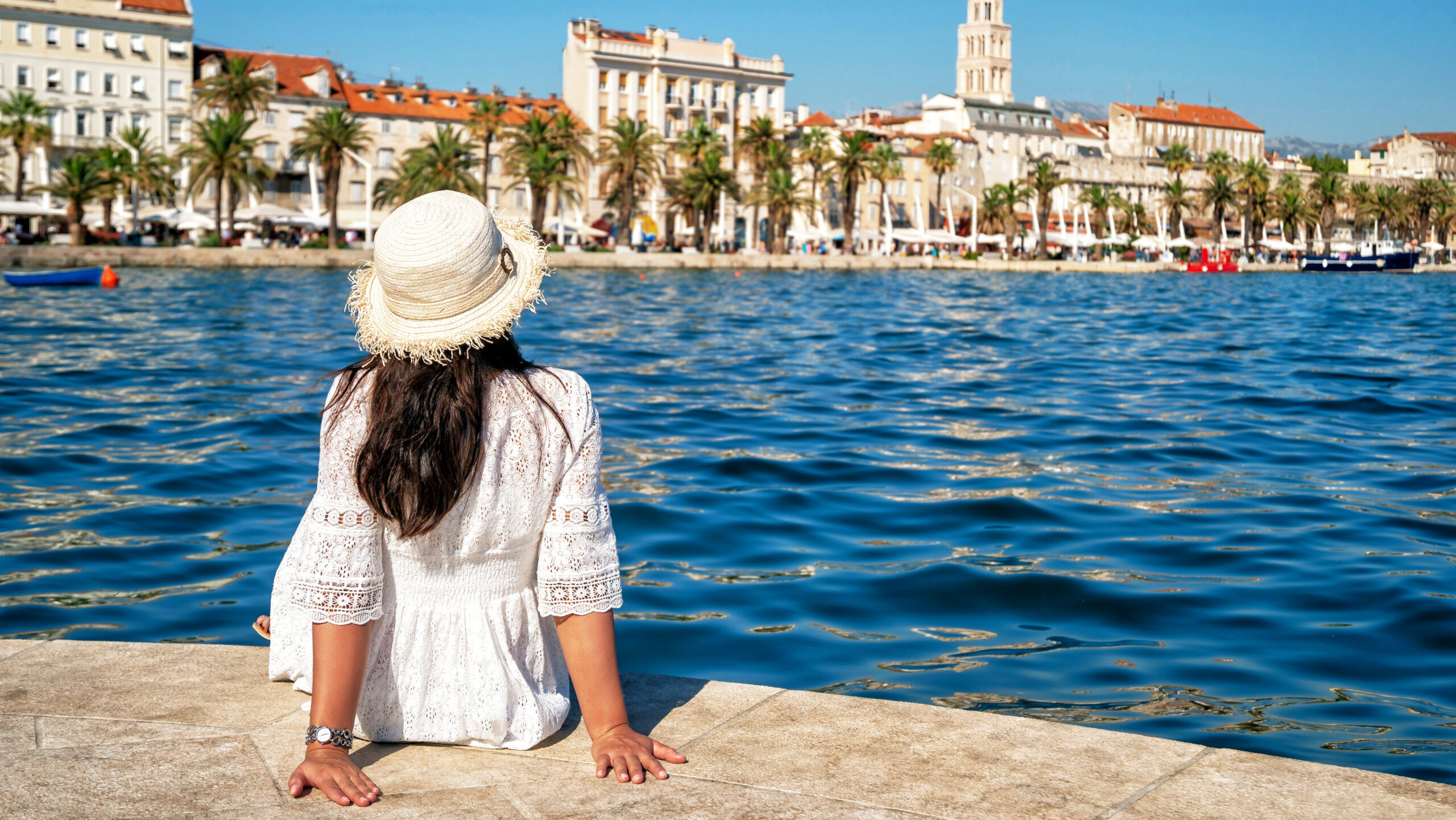 woman sitting alone looking out at the ocean with the harbor of Split, Croatia in the distance