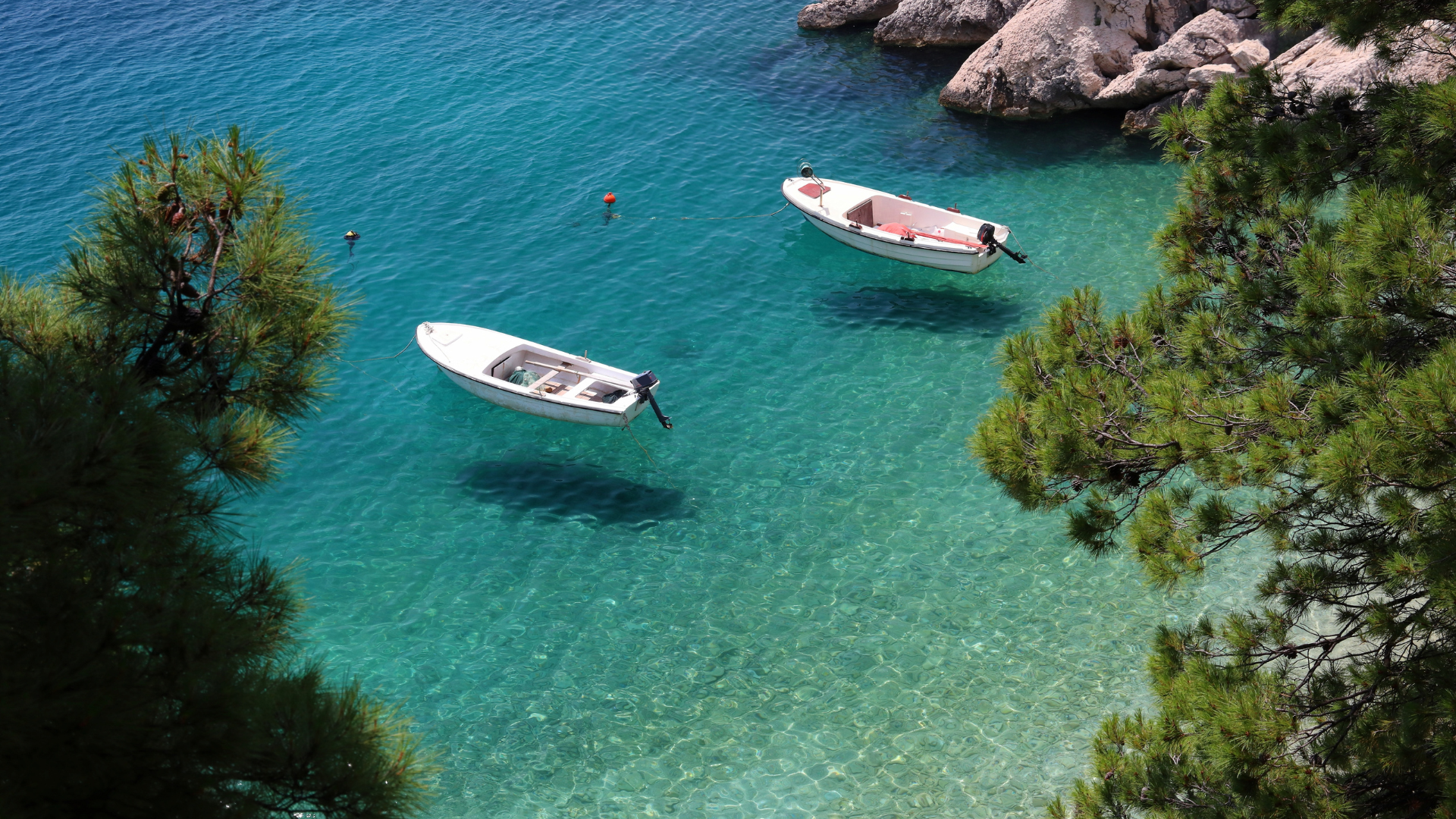 Two small motorboats floating in clear turquoise waters in the best beach town in Croatia