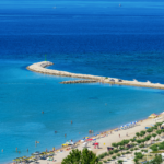 Beach with blue waters and a pier stretching into the distance