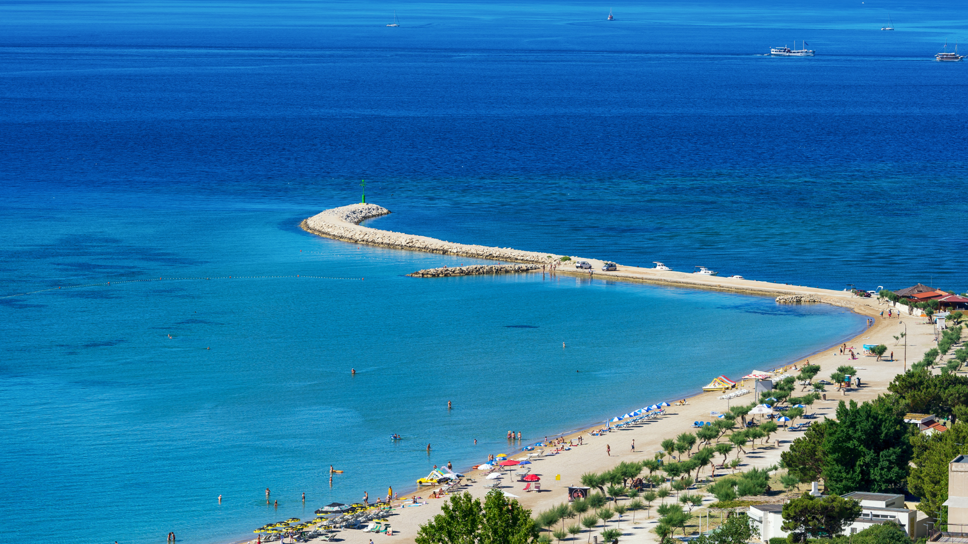 Beach with blue waters and a pier stretching into the distance